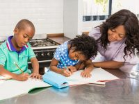 Children doing homework with their mother in the kitchen
