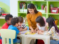 Asian female teacher teaching mixed race kids reading book in classroom,Kindergarten pre school concept.